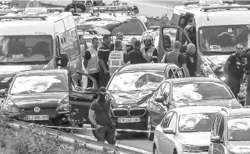  ??  ?? File photo shows police officers and emergency workers standing next to a damaged BMW car with a broken windscreen, after the police arrested a suspect on the A16 motorway, near Marquise, northern France. — AFP photo