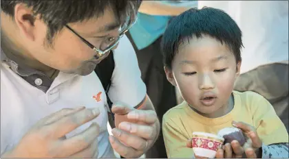  ?? LIPO CHING — STAFF ARCHIVES ?? John Li, left, of Fremont, helps his son Ian Li, right, use some ube-scented clay to make a Chinese mooncake at a pop-up installati­on at the Children’s Discovery Museum. The museum plans to use a $100,000grant from the National Endowment for the Arts to restore an arts specialist position for its performing and visual arts programs.