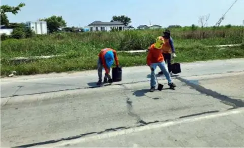  ??  ?? MEN AT WORK
Workers cover pot holes along the Mac Arthur highway in Sto. Domingo, Minalin, Pampanga.