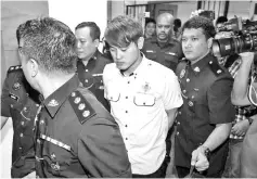  ??  ?? The accused being led by policemen at the Ampang Jaya courthouse yesterday.