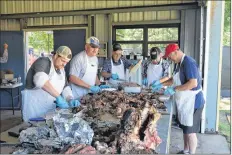  ?? CHRIS SAULNIER ?? Dana Sanford, left, alongside some more steer roasting volunteers as they work quickly to ensure the hungry crowd gets their beef.