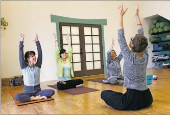  ?? Courtesy photo ?? Students learn to stretch and breathe during yoga classes at Aurafitnes­s, which also offers classes in Tai Chi and Qigong.