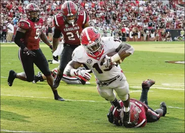  ?? CURTIS COMPTON / CCOMPTON@AJC.COM ?? UGA running back Elijah Holyfield breaks the tackle of South Carolina linebacker T.J. Brunson and dives into the end zone for a touchdown and a 41-10 lead in the third quarter Saturday.