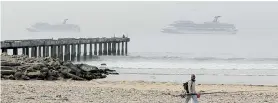  ?? Picture: FREDLIN ADRIAAN ?? NEW ARRIVALS: A fisherman walks near the New Brighton Pier yesterday with the Carnival Liberty, left, and Carnival Conquest in the background