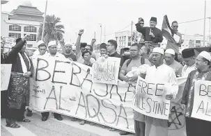  ?? — Gambar Bernama ?? BANTAHAN: Mohd Ali (berdiri belakang) melaungkan ‘hancur-hancur Israel’ ketika bersama membantah perlakuan Zionis Israel yang menghalang kemasukan umat Islam ke Masjid Al-Aqsa selepas solat jumaat di hadapan perkaranga­n Masjid Al-Azim Bukit Palah,...