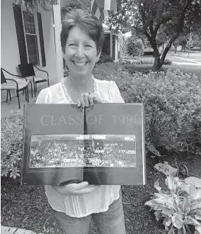  ?? [COURTESY OF CHRISTY DEWEES] ?? Christy Dewees poses at her Worthingto­n home with a yearbook photo of her 1990 graduation class from Worthingto­n High School. Her 30th reunion was canceled due to COVID-19.