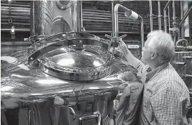  ?? AP Photo/Bruce Schreiner, File ?? ■ In this Nov. 13, 2013, file photo, Charlie Downs, the artisanal craft distiller at a new Heaven Hill Distilleri­es, Louisville, Ky., checks gauges on a still that will produce small batches of whiskey.