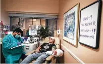  ?? Brett Coomer / Staff photograph­er ?? Alfredo Gutierrez, left, fills out paperwork as Conner Scott donates plasma at Houston Methodist Hospital on May 15. Scott, a Texas A&M sophomore, recovered from COVID-19 in late March.