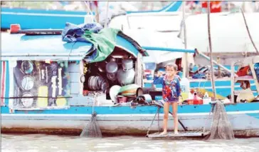  ?? HONG MENEA ?? A boy stands on a boat that doubles as a home in Phnom Penh’s Chroy Changvar district on Monday.