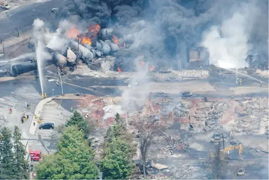  ?? PAUL CHIASSON/ CANADIAN PRESS ?? Smoke rises from derailed railway cars that were carrying crude oil through Lac- Mégantic, Que., Saturday . The disaster could prompt additional safety measures.