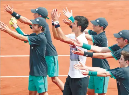  ?? AP FOTO ?? NOVAK THE CHARMER. Novak Djokovic celebrates his first round win with the ball boys at the French Open. Djokovic has been known for being friendly to the ball boys and ball girls, chilling with them during breaks and asking them to celebrate with him.