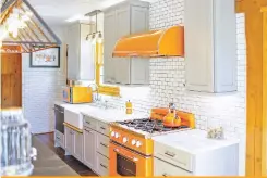  ?? BRAND VIVA VIA WASHINGTON POST ?? An Evergreen, Colo., kitchen uses bright orange Big Chill appliances — the microwave, stove and range hood — to contrast more neutral cabinetry.