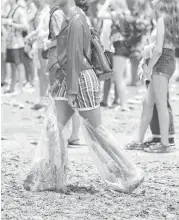  ??  ?? One festivalgo­er gets creative with her footwear after the rain turned Eleanor Tinsley Park into a sea of mud.