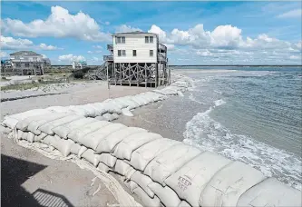  ?? CHUCK BURTON THE ASSOCIATED PRESS ?? Sand bags surround homes on North Topsail Beach, N.C., as hurricane Florence threatens the coast. The shift in the projected track had areas that once thought they were out of range worried.