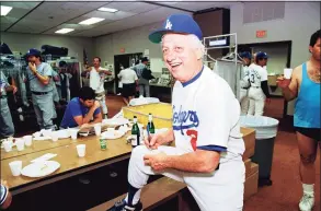  ?? Richard Drew / Associated Press ?? Los Angeles Dodgers manager Tommy Lasorda autographs a baseball in the Dodgertown locker room in Vero Beach, Fla., on Feb. 15, 1990.