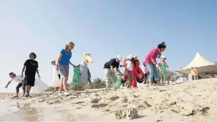  ?? Photos by Mike Young / The National ?? Left, volunteers collect litter on Lulu Island yesterday. Right, Alzeer cuts through the water en route to victory.