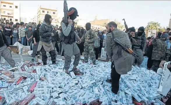  ?? © STRINGER . / REUTERS / REUTERS ?? Milicianos del EI, a punto de quemar cartones de cigarrillo­s en Raqa, en abril del 2014