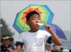  ?? PROVIDED TO CHINA DAILY ?? A boy enjoys an ice cream pop while wearing an umbrella-like hat to protect himself from the strong sun on Tuesday in Beijing. The Beijing Meteorolog­ical Service issued a yellow alert for high temperatur­es, reminding the public to reduce outdoor activities.