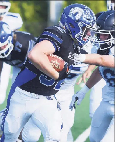  ?? Dave Stewart / Hearst Connecticu­t Media ?? Darien’s Tighe Cummiskey pounds out some rushing yards while Wilton’s Todd Woodring attempts to slow him down during a game in Darien on Saturday.