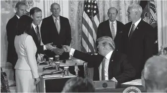  ?? Alex Wong / Getty Images ?? President Donald Trump hands the pen to NASA Administra­tor Jim Bridenstin­e after he signed an executive order during a meeting of the National Space Council.