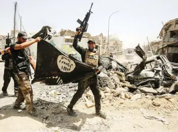  ?? AHMAD AL-RUBAYE / AFP / GETTY IMAGES FILES ?? Members of the Iraqi Counter-Terrorism Service cheer as they carry the flag of the Islamic State group in the Old City of Mosul on July 2, 2017, during the offensive to retake the city from the Islamist group.