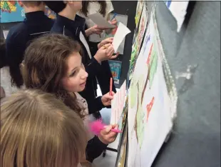  ?? H John Voorhees III / Hearst Connecticu­t Media ?? St. Rose of Lima School student Bernadette Biasetti, of Brookfield, looks at an art exhibit of work created by Ukrainian students. The exhibit was organized by art teacher Meagan Ferriter on Thursday in Newtown. The work was created before the Russian invasion.