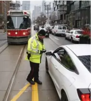  ?? BERNARD WEIL/TORONTO STAR ?? A police officer gives a driver a warning that they can no longer drive more than a block on King St. before turning right.