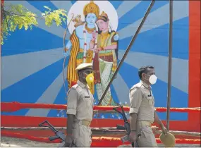  ?? RAJESH KUMAR SINGH ?? Policemen walk past an image of Hindu god Ram on the eve of a groundbrea­king ceremony of a temple dedicated to Ram in Ayodhya, India, Tuesday, Aug. 4, 2020. Wednesday’s groundbrea­king ceremony follows a ruling by India’s Supreme Court last November favoring the building of a Hindu temple on the disputed site in Uttar Pradesh state. Hindus believe their god Ram was born at the site and claim that the Muslim Emperor Babur built a mosque on top of a temple there. The 16th century Babri Masjid mosque was destroyed by Hindu hard-liners in December 1992, sparking massive Hindu-muslim violence that left some 2,000 people dead.