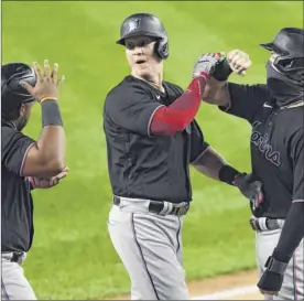  ?? Sarah Stier / Getty Images ?? Garrett Cooper, center, celebrates with teammates after his threerun home run in the first inning Friday against the Yankees at Yankee Stadium. That was all of Miami’s runs until the 10th inning.