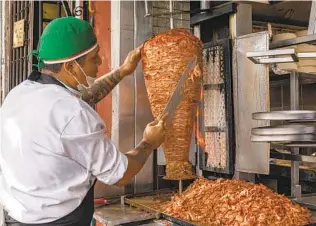  ?? ADRIAN WILSON THE NEW YORK TIMES ?? A vendor carves meat in Mexico City.