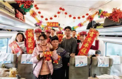  ??  ?? Attendents celebrate the Chinese Lunar New Year with passengers on the G89 train heading from Beijing to Chengdu. by Chen Jian