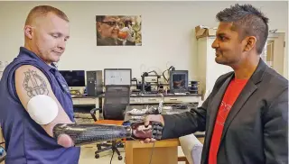  ??  ?? This undated handout photo released by the Northweste­rn University on November 20, 2019, shows retired US Army Sergeant Garrett Anderson (left) shaking hands with his prosthetic arm while wearing Northweste­rn University’s wireless patch, a new secondskin ‘virtual reality’ technology which duplicates the sense of touch