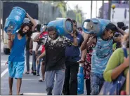  ?? (File Photo/AP/Rafiq Maqbool) ?? People carry gas cylinders July 12 after they bought them at a distributi­on center in Colombo, Sri Lanka.