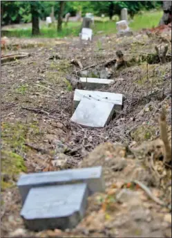  ?? Staff Photos by Jake Daniels ?? Top photo: David Young points out the faded letters in an obelisk at the peak of the Pleasant Gardens Cemetery. Bottom photo: Headstones are seen fallen into sunken graves at the cemetery Thursday.