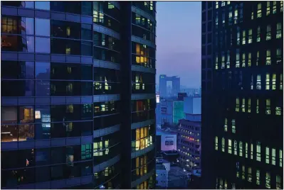  ?? (Los Angeles Times/TNS/Marcus Yam) ?? Apartment buildings in Seoul light up in the evening as people get home from work. The South Korean capital’s 10 million people are packed into a density that is 60% higher than New York City.