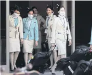  ??  ?? GROWING FEARS: A flight crew from Korean Air wearing protective masks depart the internatio­nal terminal at Los Angeles Internatio­nal Airport on Friday.