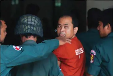  ?? HONG MENEA ?? Political analyst Kim Sok is escorted into the Phnom Penh Municipal Court for his trial on defamation and incitement charges yesterday.