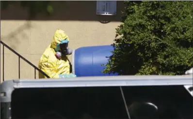  ?? The Associated Press ?? WASTE BARRELS: In this Oct. 3 photo, a hazardous material cleaner removes a blue barrel from the apartment in Dallas, where Thomas Eric Duncan, the Ebola patient who traveled from Liberia to Dallas stayed. The apartment contents were incinerate­d but...