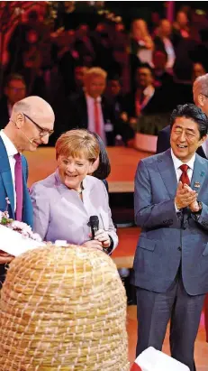  ?? FOTO: ANDERSEN/AFP ?? Routiniert lässt sich Angela Merkel mit Japans Regierungs­chef Shinzo Abe (r.) auf der Cebit einen Sensor für einen Bienenstoc­k zeigen. Viele in der Union wünschen sich von ihrer Spitzenkan­didatin mehr Attacke.