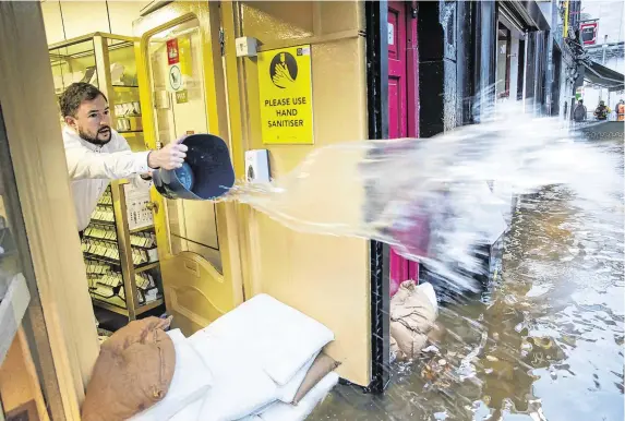  ?? PHOTO: DARAGH McSWEENEY/PROVISION ?? Storm surge: Jeweller Roland Kennedy tries to limit the damage in his shop following flooding on Winthrop Street in Cork city.