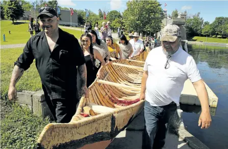  ?? CLIFFORD SKARSTEDT/EXAMINER ?? Miawpukek First Nation members move a birch bark canoe make by Miawpukek master builders and youth as part of a ceremony hosted by the Canadian Canoe Museum to mark National Aboriginal Day on Wednesday on the Trent Severn Waterway canal below Lock 21...