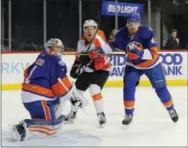  ?? RICH SCHULTZ — THE ASSOCIATED PRESS ?? Flyers center Nick Cousins (52) and Islanders defenseman Scott Mayfield attempts to control the airborne puck in front of Islander goalie Thomas Greiss during the first period Sunday in New York.