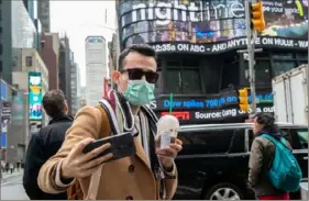  ?? Mary Altaffer/Associated Press ?? Justin Dalipi of Albania wears a mask as a precaution against the new coronaviru­s as he takes a selfie Tuesday in Times Square in New York City.