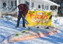  ?? ERIC MCCARTHY/JOURNAL PIONEER ?? Tyne Valley mayor Jeff Noye pretends to dig in to the Grigg family’s entry in the Tyne Valley Winter Carnival’s snow sculpture competitio­n. The theme of the carnival and the snow sculpture competitio­n is Kraft Hockeyvill­e.