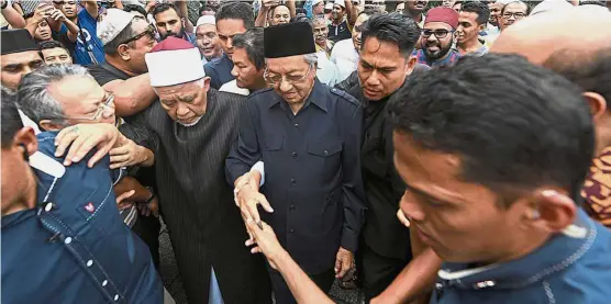  ??  ?? In the groove again: Dr Mahathir has been mobbed wherever he goes since returning to the post he left 15 years ago. He is seen here making his way to his car as National Mosque chief imam Tan Sri Syaikh Ismail Muhammad holds on to his hand.