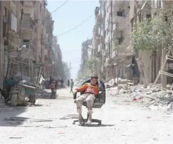  ?? — Reuters ?? A boy sits on a chair along a damaged street at the city of Douma in Damascus, Syria, on Tuesday.