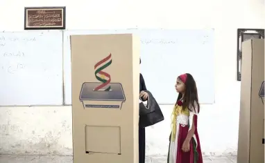  ?? PICTURE: AP ?? DECISIVE MOMENT: A girl dressed in the colours of the Kurdish flag looks at her mother as she votes inside a booth for Kurdish independen­ce in the city of Kirkuk, yesterday.