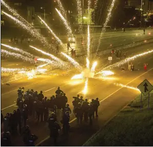  ?? (Arkansas Democrat-Gazette/Stephen Swofford) ?? Protesters throw fireworks at police officers Saturday evening as they block Interstate 630 during a protest in downtown Little Rock over the killing of George Floyd in Minneapoli­s. More photos at arkansason­line.com/531lr/.