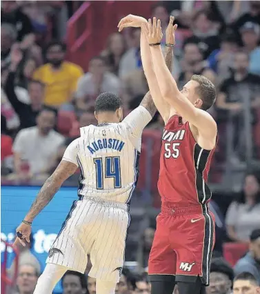  ?? MICHAEL LAUGHLIN/SUN SENTINEL ?? The Heat’s Duncan Robinson hits a 3-pointer over the Magic’s D.J. Augustin during the first half Wednesday night in Miami