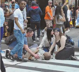  ?? AP PHOTOS ?? SIDEWALK HORROR: Several bystanders, above, tend to a man who was struck by a car that was steered onto a sidewalk in Times Square in New York City. Below, the vehicle comes to a rest with its right wheels in the air after striking 23 people, killing...